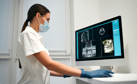 Dental professional looking at x-rays of teeth on a computer