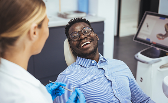 Man in the treatment chair grinning at his orthodontist