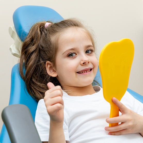Young girl in the treatment chair giving a thumbs up