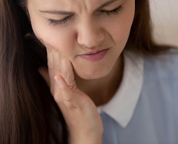 Woman holding her cheek in pain needing emergency orthodontic care in Columbus