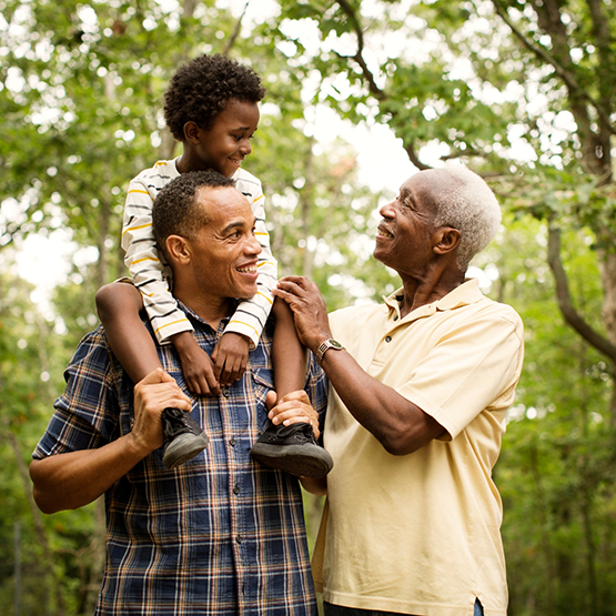 A young boy with his father and grandfather in the woods