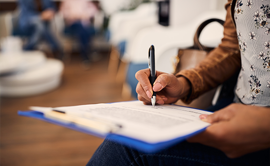 Person filling out paperwork on a clipboard