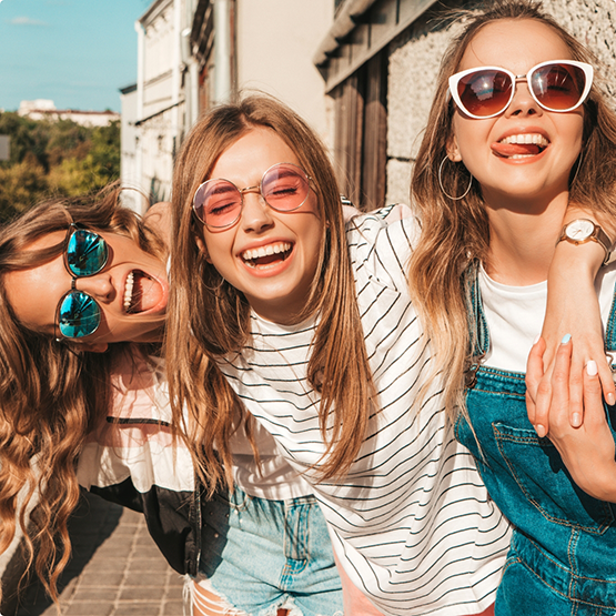 Three teenage girls laughing together on a city street