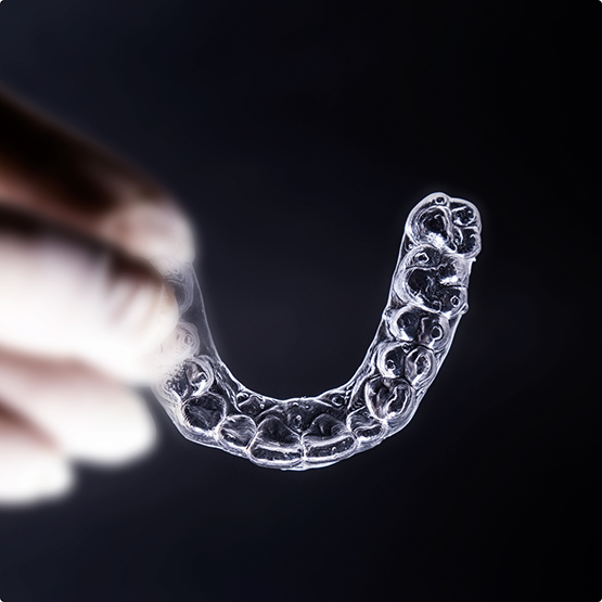 Gloved hand holding an aligner