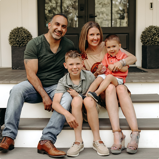 Doctor Mason sitting on front porch steps with his wife and two children