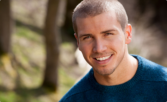 Man in a blue sweater smiling outdoors