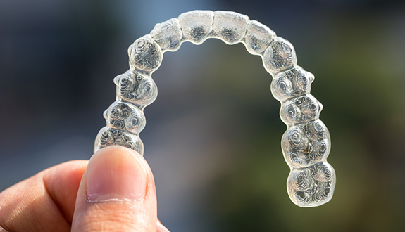 Hand holding a clear aligner