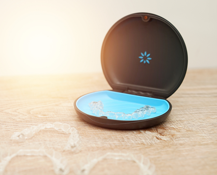 Two Invisalign clear aligners in their plastic storage case