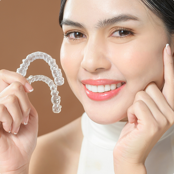 Smiling woman holding two Invisalign trays