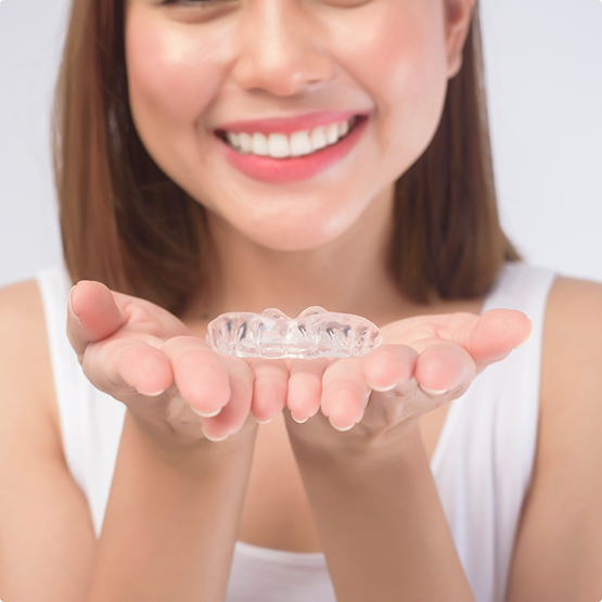 Smiling woman holding Invisalign in her open palms