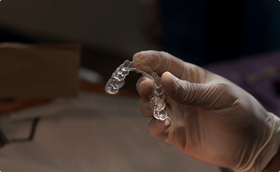 Gloved hand holding an Invisalign aligner