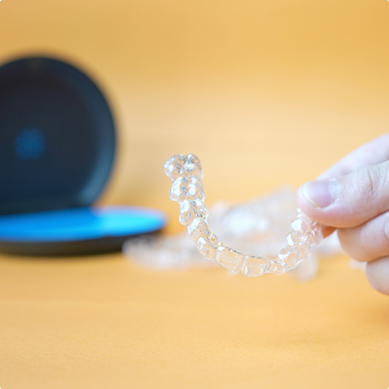 Close up of a hand holding an Invisalign tray