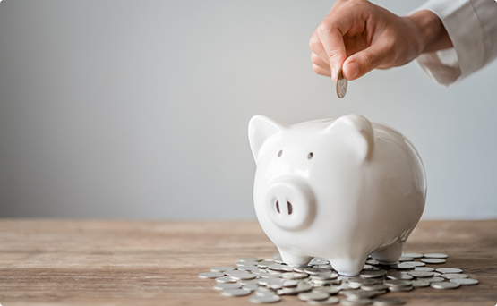 Person putting a coin into a piggy bank