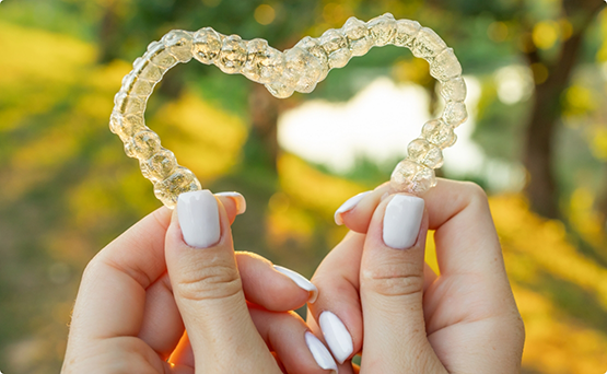 Hands holding two aligners in a heart shape