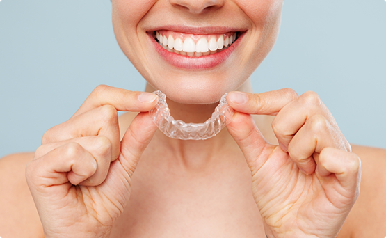 Grinning person holding an aligner