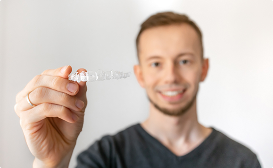 Man smiling and holding an aligner