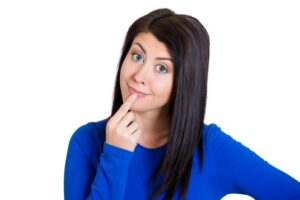 Woman in blue shirt wearing curious expression