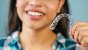 Young woman holding Invisalign aligner